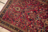 Meandering vine and pearl seed borders on a vintage raspberry red German Sarouk rug.