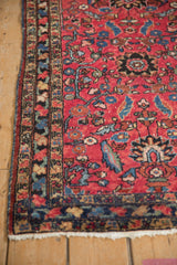 Close-up of the antique Lilihan rug's raspberry field with expressive sapphire blue leaves and vines.