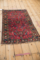 Angled view of antique Lilihan rug corner, raspberry red field, gem-toned floral border, and fringe.