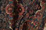 Folded Persian Dargezine rug, intricate Herati pattern in dusty blue and raspberry red.