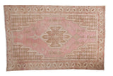 Distressed Mazlaghan rug, serrated medallion, pinwheel blossoms, pink and brown tones.