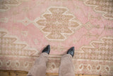 Distressed vintage Mazlaghan rug with sharp serrated medallion, pink and pale coffee brown vinery.