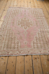 Distressed vintage Mazlaghan rug with pale pink and sand corner spandrel and border patterns.