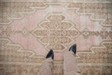 Pink and brown vintage Mazlaghan rug detail showing serrated medallion and pile wear.