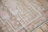 Mazlaghan rug corner detail: serrated spandrel with pinwheel motifs, worn pink, brown, ivory pile.