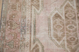 Worn pile detail of the vintage Mazlaghan rug, featuring pale pink and brown geometric motifs.