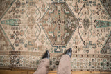 Hexagonal medallion with tribal Herati motifs in distressed beige, brown, and emerald green.
