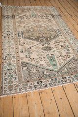 Distressed Hamadan rug showing geometric medallion, faded emerald, and beige border.