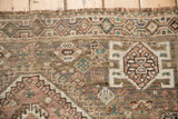 Hand-knotted Qashqai rug close-up: geometric border, even wear, dusty mauve, and sand hues.
