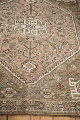 Dusty mauve Qashqai field with worn pile, stylized birds, and geometric border.