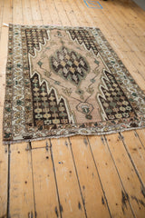 Vintage Mazlaghan rug corner with chocolate brown stepped vinery, showing wear and fringe.