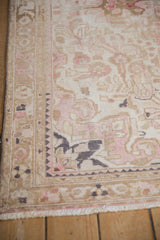 Distressed vintage Hamadan rug corner detail, with worn ivory, pink, and slate blue patterns.