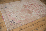 Distressed vintage Hamadan rug corner with pink floral motifs, machine binding, and even wear.