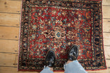 Hand-knotted vintage Bijar rug, red floral field, dark border, shown with feet.