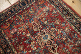 Intricate cherry red field with floral blossoms, pinwheel motifs, and navy Herati Samovar border.