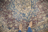 Faded cobalt blue, violet, and ivory floral arabesque patterns on a distressed Sparta carpet.