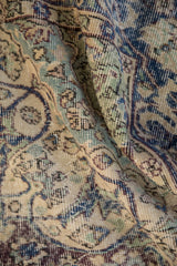 Decorative worn texture and faded blue, green, ivory floral arabesques.