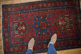Vintage Karaja rug, cherry red field with sapphire blue geometric medallion, showing human feet.
