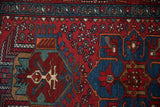 Vintage Karaja rug with cherry red pinwheel florals, sapphire blue geometric motif, dusty teal border.