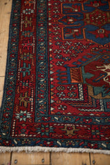 Vintage Karaja rug corner with cherry red pinwheel field, sapphire blue starburst border, and fringe.