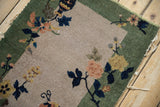 Art Deco rug corner: celadon green border, antique ivory field, blush floral motifs.