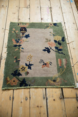 Lower corner of Nichols Art Deco mat, celadon green border, blush floral, bound edge remnants.