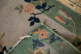 Antique Nichols Art Deco rug detail: blush floral, celadon green, woven foundation, worn edges.