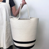 Large woven cotton rope basket with handles, featuring an off-white body and black striped base.
