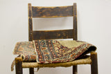 Worn low pile texture on antique Persian Kerman rug section, showcasing khaki, maroon, navy designs.