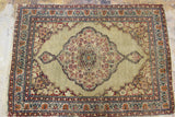 Khaki field and maroon central medallion showing wear on the antique Kerman rug.