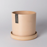 Muted coral cylindrical planter with a natural textured finish and matching saucer.