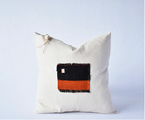 Vintage Aguayo weaving pillow with vibrant black and orange textile patch on off-white canvas, 20x20.