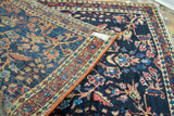 Intricate traditional motifs on a vintage Sarouk rug's dark blue field, showing red cording.