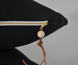 Black linen pillow with exposed brass zipper, genuine leather pull, and wood bead.