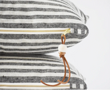 Striped linen pillow with exposed brass zipper and brown leather bead pull.
