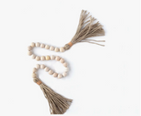 Handcrafted wood bead garland with jute tassels and leather tie details.
