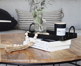 Decorative wood bead garland with jute tassels draped over books on a coffee table.