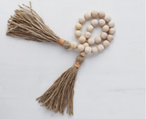 Handcrafted wood bead garland with thick jute tassels and tan leather details.