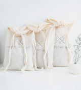 Three natural canvas drawstring bags, each printed with the Twenty Two West logo.
