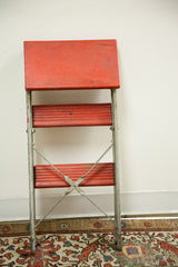 Industrial red and silver step stool's lower steps, metal cross-bracing, and patina.