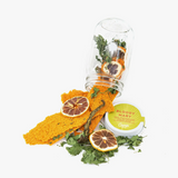 Camp Craft Bloody Mary kit: spilled dried lemon, green herbs, orange crisps, and green lid.