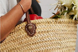 Handmade Moroccan shopping bag with natural woven straw and a stitched brown leather strap.