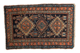 Vintage Karaja rug with geometric stepped diamond medallions in terracotta, gold, and blue on a navy field.
