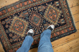 An overhead view of a vintage Karaja rug, showing the scale of its geometric pattern and texture.