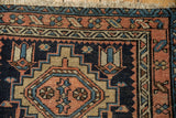 Corner of a vintage Karaja rug showing primitive geometric motifs in terracotta, navy, and sky blue.