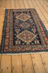 Vintage Karaja rug viewed from an angle, showing its stepped diamond medallions on a navy blue ground.