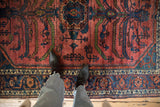 Detail of a fine Lilihan carpet's raspberry red pile, featuring sprawling serrated leaves in navy blue and green.