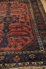Angled view of a vintage Lilihan carpet's tree of life motif and complex navy blue main border.