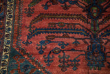 Textured pile of a vintage Lilihan carpet showing raised white knots among serrated navy blue leaves on a red field.