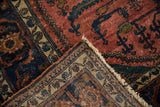 Folded corner of a vintage Lilihan carpet showing the raspberry red pile, ivory floral border, and hand-knotted back.
